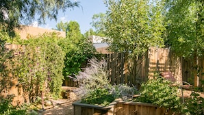 Un jardin agrémenté de jardinières en bois, d’une clôture en bois et de différentes plantes.