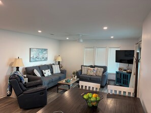 A living room with a sofa, armchair, coffee table, and a TV. - AUGUST..STILL SUMMER..LOWER RATES ..LESS CROWDS!!! (Gulf Shores)