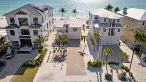 Une propriété située en bord de mer, comprenant plusieurs bâtiments, une allée pavée et des palmiers.