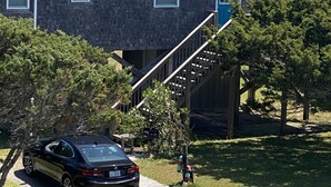 Un immeuble résidentiel doté d’un porche à l’avant, d’un escalier menant au deuxième étage et d’une voiture garée dans l’allée.