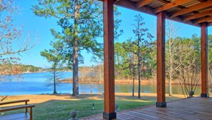 A wooden deck with a bench overlooking a lake, surrounded by trees.