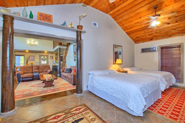 A spacious room with a large bed, a sitting area with a sofa and chairs, and a wooden ceiling.