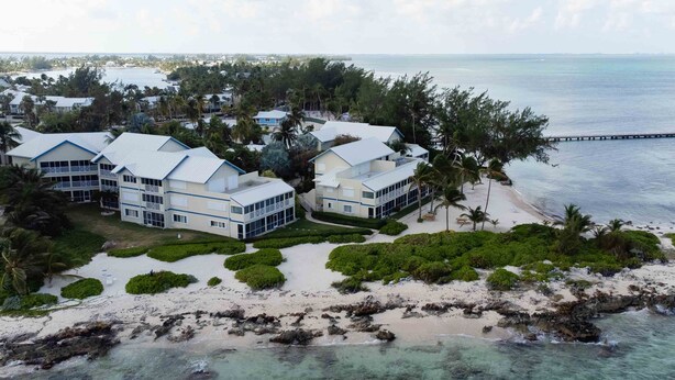 A coastal resort with multiple buildings, a beach, and a pier.