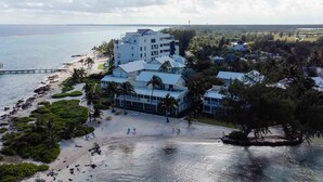 A beachfront hotel with multiple buildings, a sandy beach, and palm trees.