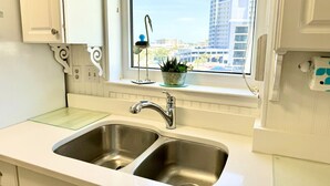 Cucina con lavello doppio, mobili bianchi e finestra vista edifici.