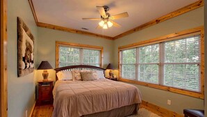 A bedroom with a large bed, wooden walls, and windows with blinds. - Beautiful lodge, 4 king bedrooms, all with private baths! 5 decks to enjoy. (SKY VALLEY)