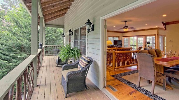 A wooden deck with wicker furniture and a dining area with a table and chairs. - Beautiful lodge, 4 king bedrooms, all with private baths! 5 decks to enjoy. (SKY VALLEY)