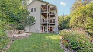 A two-story building with a covered porch and a stone retaining wall. - Beautiful lodge, 4 king bedrooms, all with private baths! 5 decks to enjoy. (SKY VALLEY)
