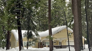 Un refugi cobert de neu amb un gran porxo i alts pins al seu voltant.