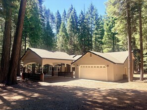Un chalet doté d’un patio couvert, d’un garage et entouré d’une forêt naturelle.