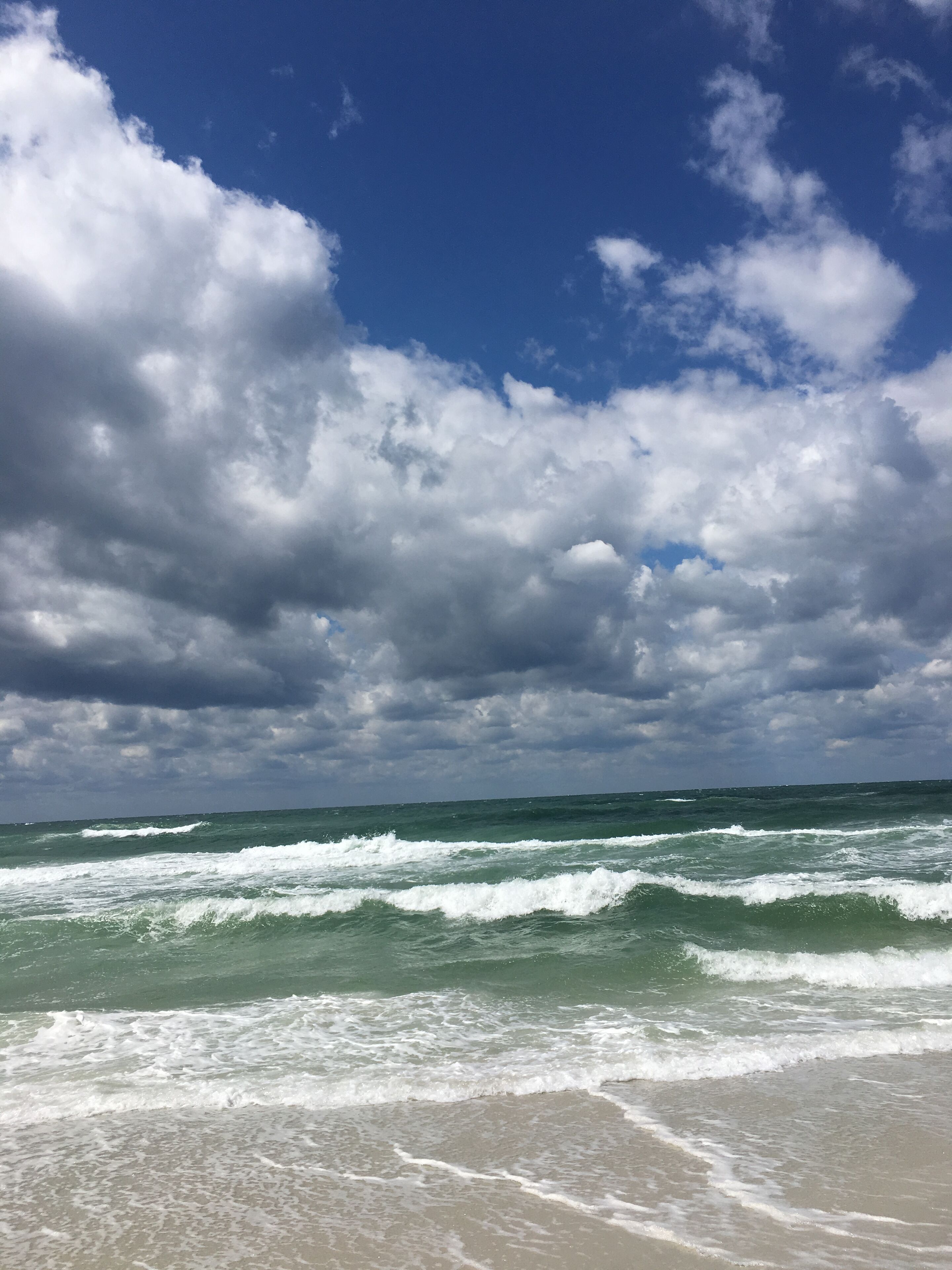 Una spiaggia con onde e un cielo nuvoloso.