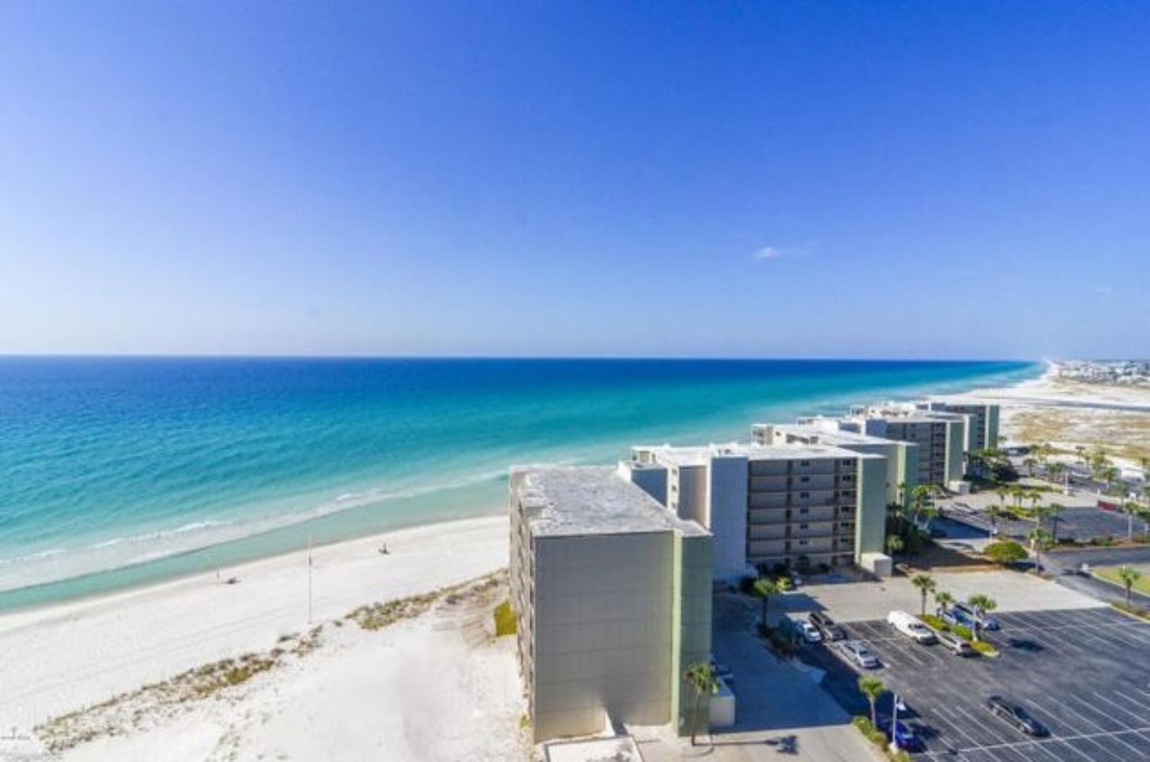 A beachfront hotel with a parking lot and ocean view.