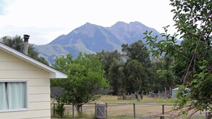 A house with a satellite dish, a fenced yard, and mountains in the background.