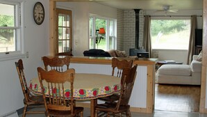 A dining area with a wooden table and chairs, a kitchen visible through an open door, and a living area with a sofa.