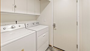 A laundry room with two white washers and dryers, a white door, and a white ceiling. - Elk Tracks Lodge (Easton)