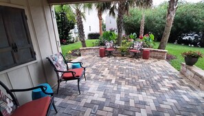 An outdoor patio with a herringbone brick pattern, outdoor furniture, and a view of a residential area.