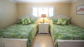 A bedroom with two single beds, a nightstand with a lamp, and a window with blinds. - Happy Place Chateau La Mer II #1301 2-Bd 2-Bth Ground Floor Private Patio (Destin)