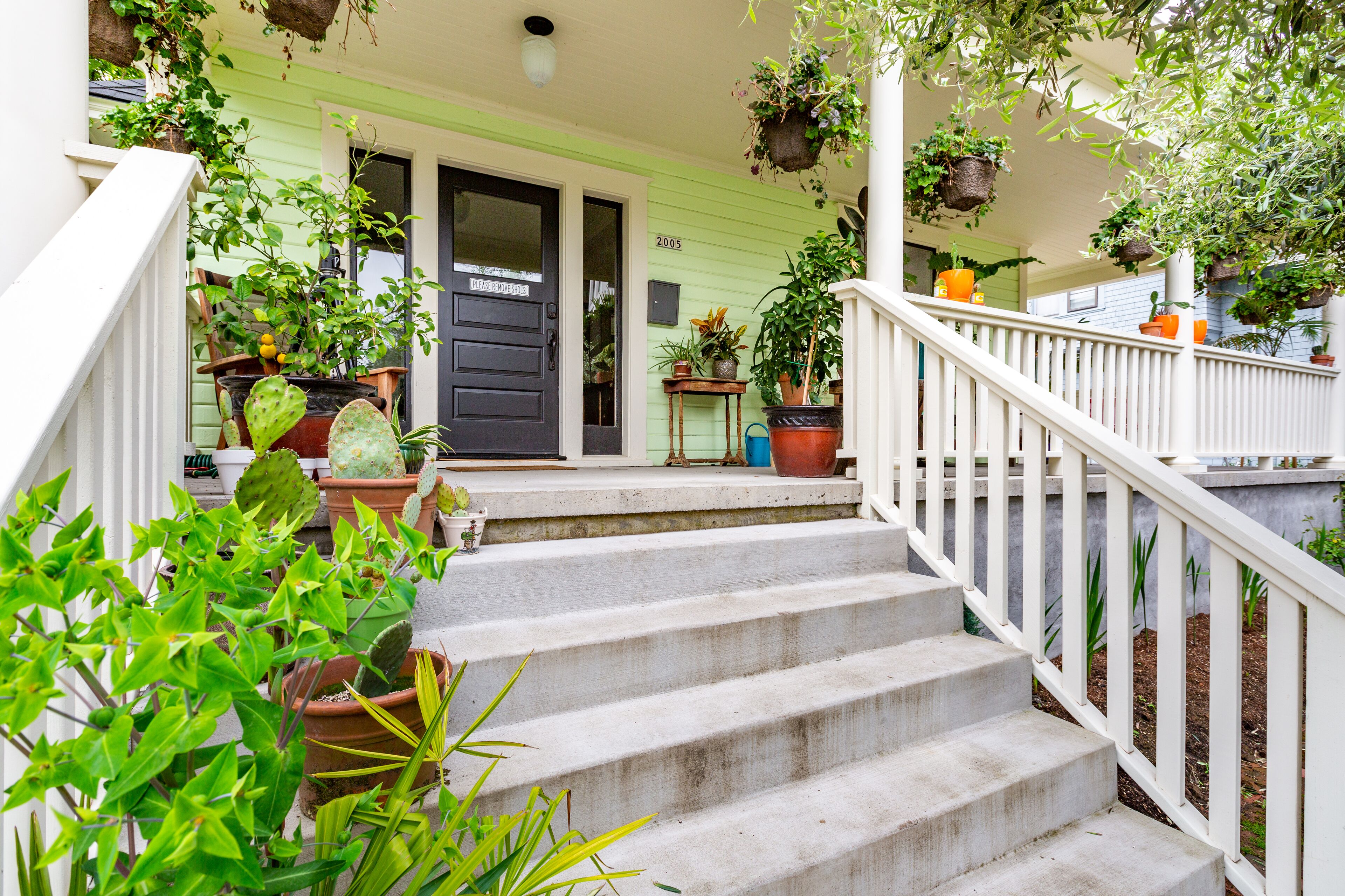 A house with a porch, steps, and various potted plants.