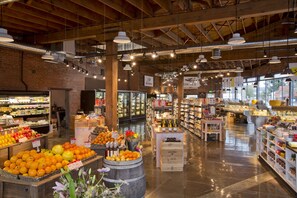 Un vaste marché couvert où l’on trouve différents stands de produits alimentaires, notamment des fruits et légumes frais et des produits de boulangerie.