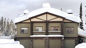 A two-story lodge with a gabled roof, multiple windows, and a snow-covered exterior.