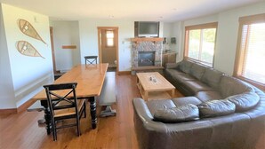 A living room with a wooden dining table, a sofa, a fireplace, and a TV.