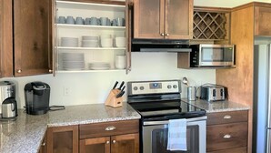 A kitchen with wooden cabinets, a microwave, a stove, and a coffee maker.