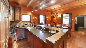 A kitchen with wooden cabinets, a large island with a sink, and a view of the outdoors through a window.
