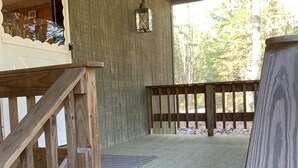 A wooden deck with a ramp leading to a covered area, a wooden bench, and a lantern on the wall.