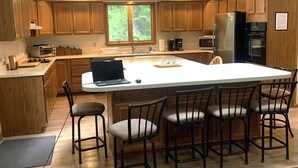 A modern kitchen with wooden cabinets, a central island, and a skylight.