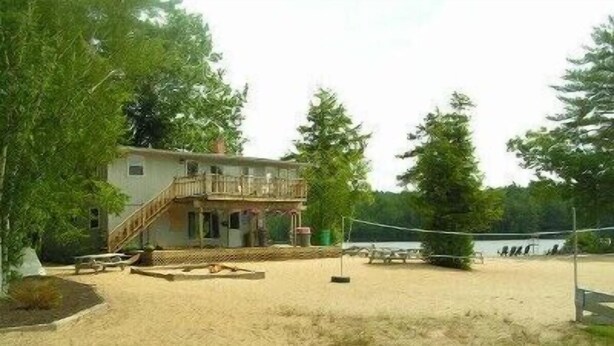 A beach house with a balcony, a sandy area, and a volleyball net.