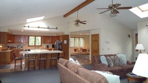 A spacious living area with a large couch, a dining table, and a kitchen area with wooden cabinets and a bar.