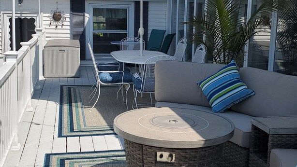 Eine überdachte Terrasse mit rundem Tisch, gepolsterten Sitzmöglichkeiten und einem gemusterten Sonnenschirm.