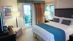 A hotel room with a bed, a desk, a chair, and a window with curtains. - Four Season Aviara                            (Carlsbad)