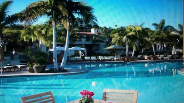 A swimming pool with lounge chairs and a table with a flower arrangement. - Four Season Aviara                            (Carlsbad)