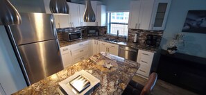 Een moderne keuken met roestvrijstalen apparatuur, witte kastjes en een granieten aanrecht.