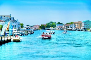 A marina with boats docked, a pier with a flag, and buildings along the waterfront.