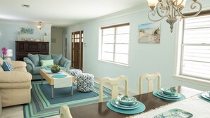 Comedor con una mesa de madera dispuesta para cuatro personas, rodeada de sillas blancas.