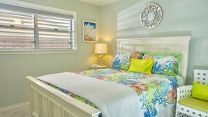Un dormitorio con cama, mesita de noche, lámpara, silla y decoración en la pared.