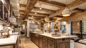 A spacious kitchen with wooden beams, a large island, and pendant lighting. - Abode at Three Bears, stunning wilderness estate (Jackson)