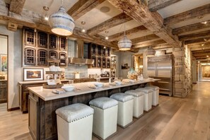 A spacious kitchen with a central island, stone accents, and exposed wooden beams. - Abode at Three Bears, stunning wilderness estate (Jackson)