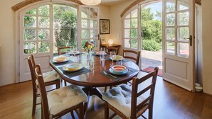 Une salle à manger avec une table ronde dressée pour six personnes, entourée de chaises en bois dotées d’assises rembourrées.