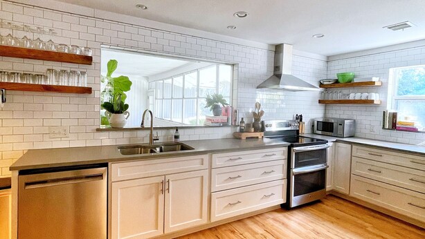 Une cuisine moderne avec des meubles blancs, un plancher en bois et un four encastré.