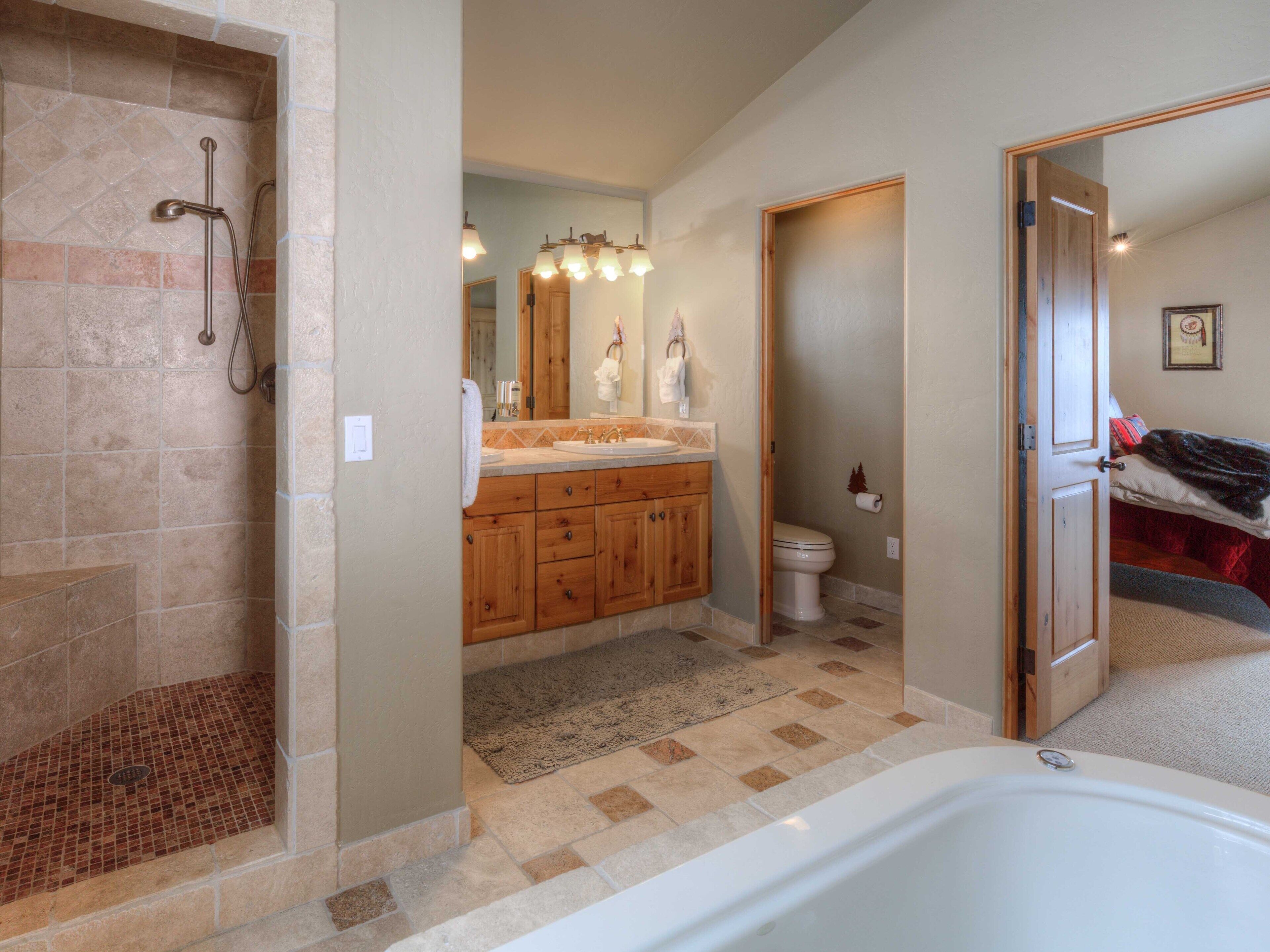 A spacious bathroom with a walk-in shower, a large bathtub, and a wooden vanity with a mirror.