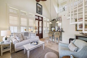 A spacious living room with a sofa, chairs, a coffee table, and a dining area with a bar.