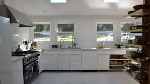 A modern kitchen with white cabinets, a stove, and a skylight. - Sabor Mexicano Vacation Retreat, (Guerneville)