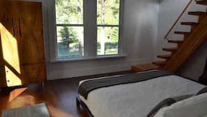 A bedroom with a bed, a window, a wooden wardrobe, and a staircase. - Sabor Mexicano Vacation Retreat, (Guerneville)