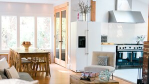 A modern kitchen with a built-in stove and oven, a dining area with wooden furniture, and a living room with a sofa and coffee table. - Sabor Mexicano Vacation Retreat, (Guerneville)