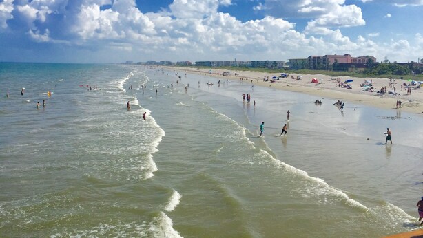 Ein Strand mit Schwimmern und Spaziergängern am Ufer.