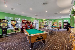 A pool table in a room with green walls and a carpeted floor.