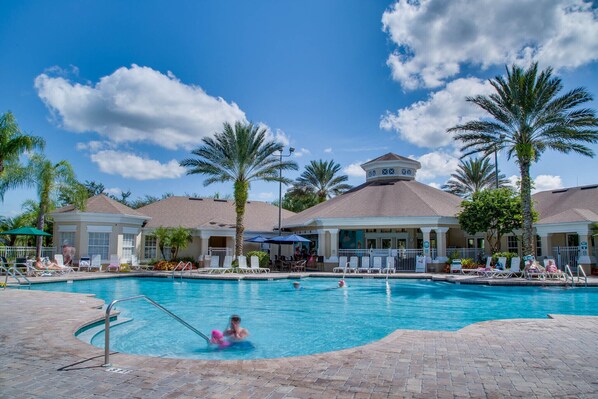 A swimming pool with lounge chairs and palm trees.
